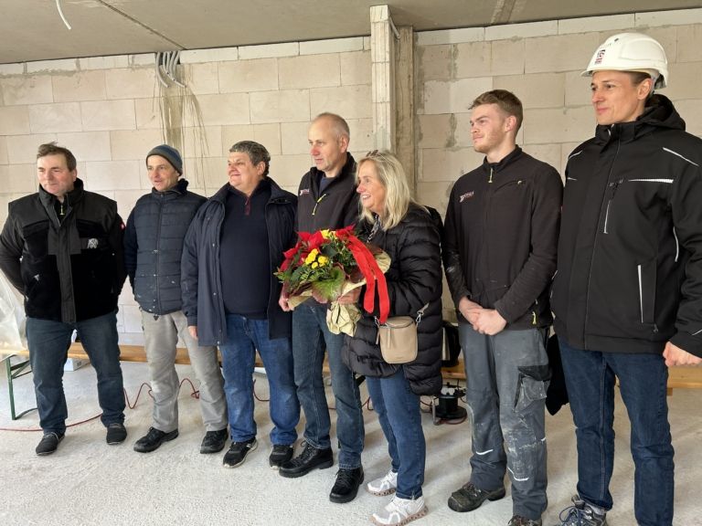 Personen auf der Baustelle, Frau mit Blumenstrauß